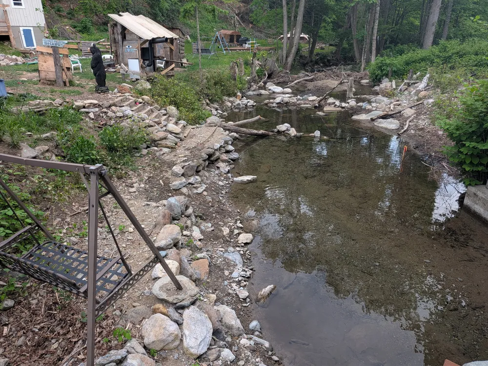 A quiet stretch of Cabin Creek on the property — shallow rocky pool with stones lining the banks, a spot for dangling feet in the water