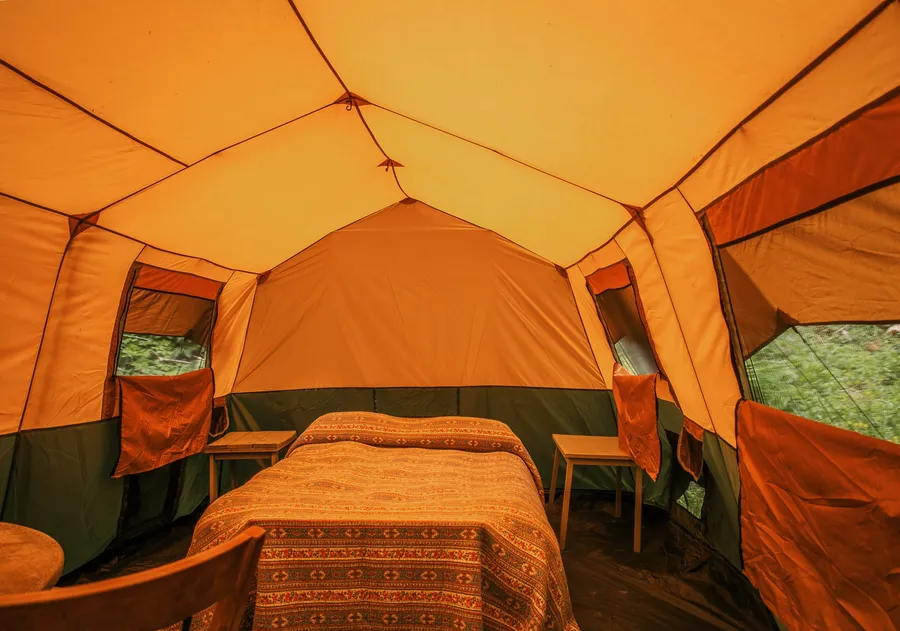 Inside the glamping tent, the queen bed made up with linen under the canvas roof